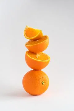 Close-up of a stack of oranges, whole and sliced, a tower of oranges on white 스톡 사진