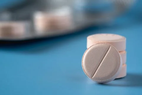 A close up of stack of pills on a blue surface Stock Photos