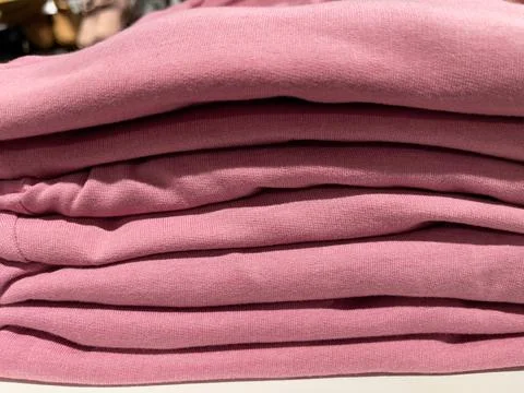 Close up of a stack of pink clothes on a shelf in a store Stock Photos