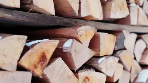 Close-up of stacked chopped firewood with light snow dusting, winter fuel Stock Footage 327554329