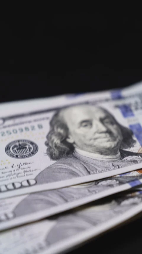 Close-up of stacked hundred-dollar bills showing detailed portraits and security Stock Footage 328124773