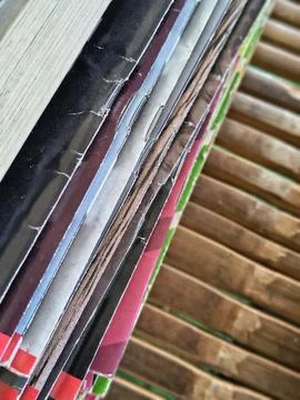 Close up of stacked old magazines with worn edges on bamboo mat. Stock Photos