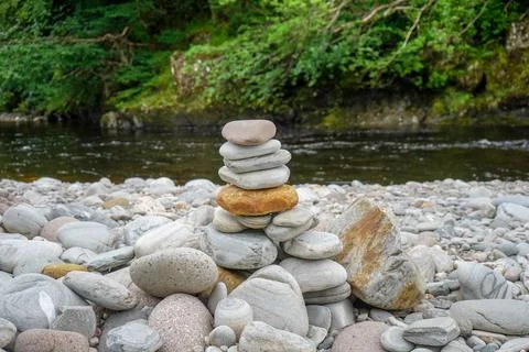 Close up of stacked pebbles with a river in the background 写真素材