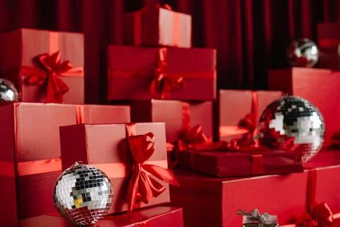 Close-up of stacked red wrapped gift boxes and silver disco balls. Stock Photos