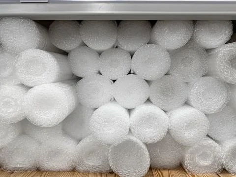 A close-up of stacked white bubble wrap rolls in a metal industrial shelf, .. Stock Photos