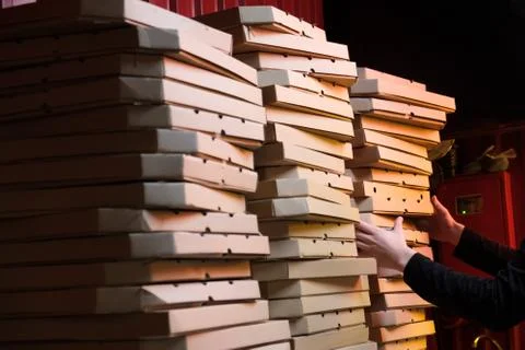 Close up of stacks with pizza boxes in low neon yellow light Stock Photos