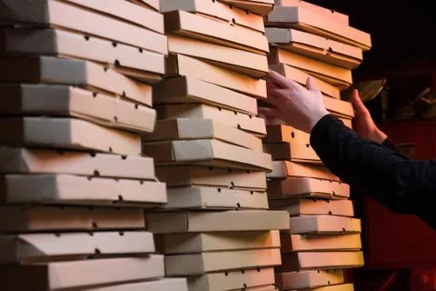 Close up of stacks with pizza boxes in low neon yellow light Stock Photos