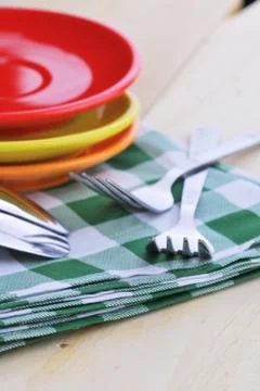Close-up of stainless fork and spoon on tablecloth with red,yellow, orange pl Stock Photos