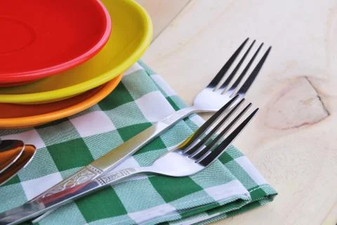 Close-up of stainless fork and spoon on tablecloth with red,yellow, orange pl Stock Photos