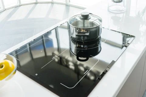 Close-up of stainless steel cooking pot and pan on induction hob in modern .. Stock Photos