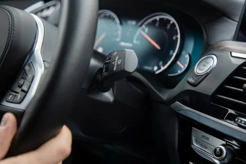 Close-up start-stop button under the steering wheel of a modern car. mans han Stock Photos