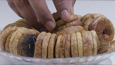 Close up static shot of hand picking up dried fig from plate on table Stock Footage 280336627