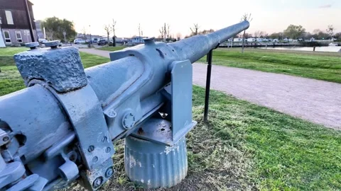 Close-up static shot of a historic grey naval cannon on display in a coastal par Stockbeeldmateriaal 332860920