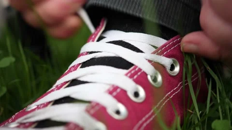 Close up static view of hands tying shoelaces on a red sneaker with white Stock Footage 138397394