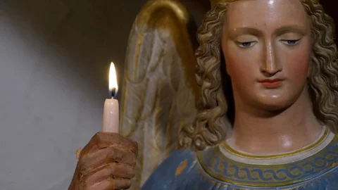 Close up of a statue of an angel holding a burning candle in his hand Vidéo 128316558