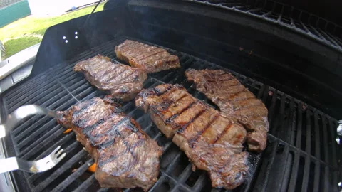 Close up of a steak getting flipped on a grill Stock Footage 147979550