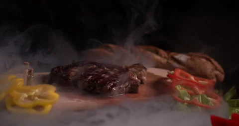 Close-up steak in smoke on a black background with spices and vegetables Stock Footage 130360993