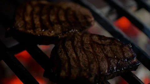 Close up of steaks on grill with fire flames, chef turns them over, slow motion Stock Footage 92705727