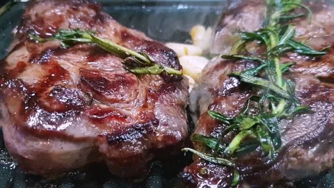 Close-up of steaks of marbled beef on the grill. Rosemary and garlic 動画素材 128440203