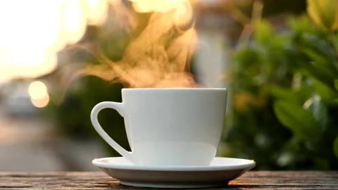 Close-up steaming hot coffee or tea cup on saucer, slow motion. Stock Footage 143276415