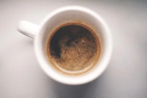 Close-up of a steaming hot cup of coffee beverage with foam in its white mug Stock Photos