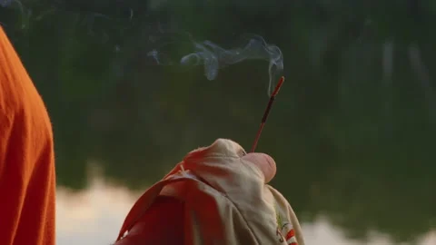 Close-up, steaming incense in the hand of a religious man in orange robe holding Stock Footage 205710468