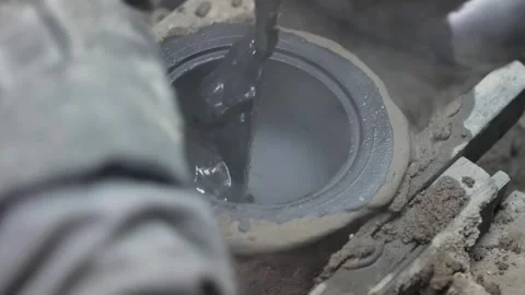 Close up of steaming liquid metal or graphite being smoothed inside a mold with Stock Footage 332230527
