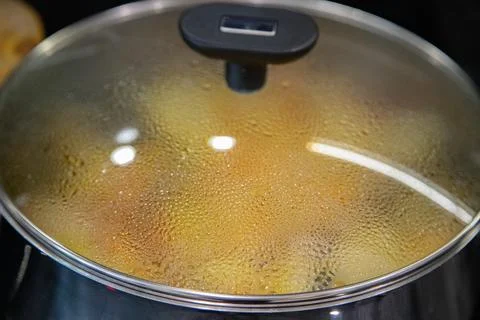 Close-up of a steaming pot with a glass lid during home cooking Stock Photos