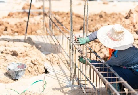 Close-up of a steel fixer assembling a rebar reinforcement cage along a tre.. 스톡 사진