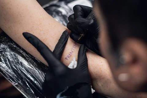 Close-up stick and poke method of tattooing a young girl's hand with the Foto stock