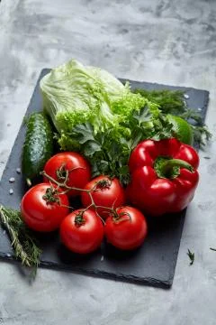 Close-up still life of assorted fresh vegetables and herbs on white textured Photos