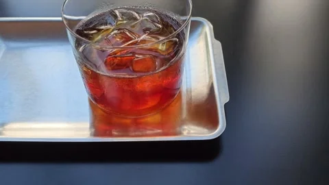 Close-up still life of iced cold brew coffee in glass on metal tray Stock Footage 344747722
