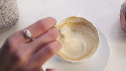 Close-up stir the coffee in the cup with a spoon from above woman Stock Footage 99666162