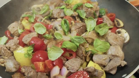 Close-up stir-frying beef and vegetables with basil in a steaming pan Stock Footage 321193424