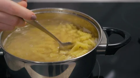 Close-Up, Stir, Woman's Hand with Spoon Stirs Pasta Cooking in a Saucepan Stock Footage 103636997