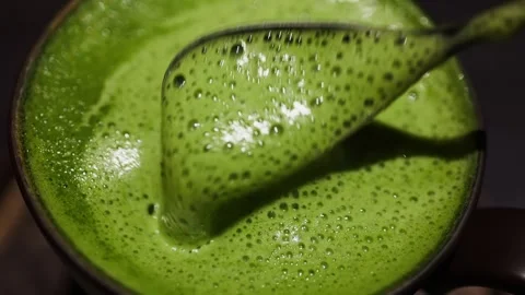 Close up stirring matcha green tea with spoon creating foam and bubbles, pr.. Stock Footage 339212495