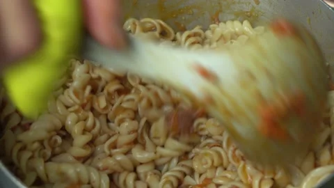 Close-up stirring red noodles in a kitchen pot. Peruvian food made at home Stock Footage 140131145