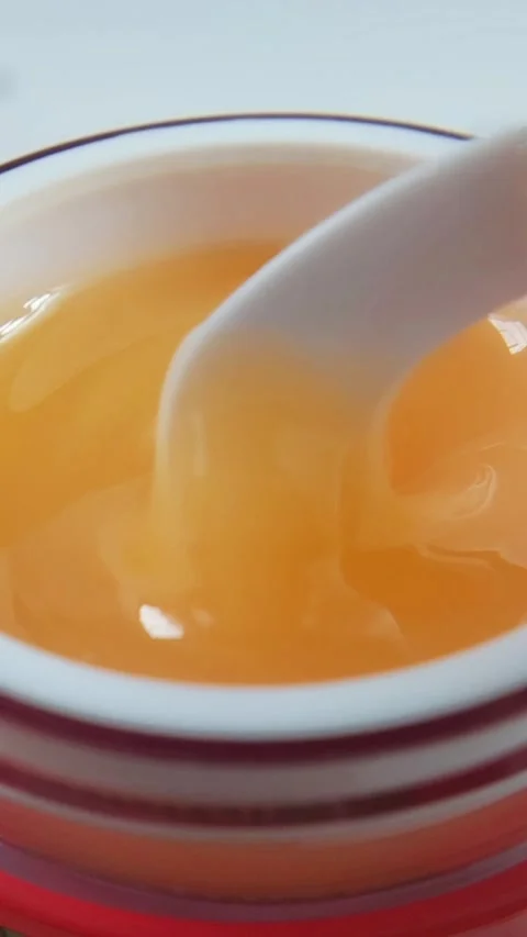 Close up of stirring thick orange liquid in red container with spoon, visco.. Stock Footage 331231512