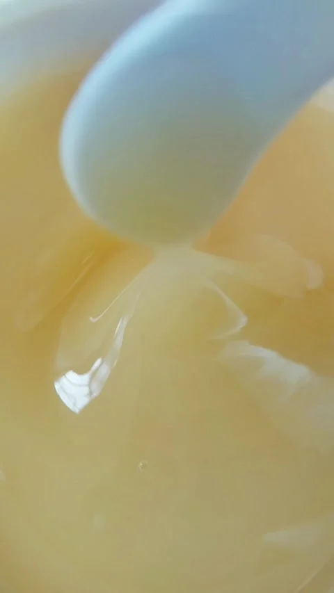 Close up of stirring thick yellow gel with spoon, bouncy chewy texture skin.. Stock Footage 331231489