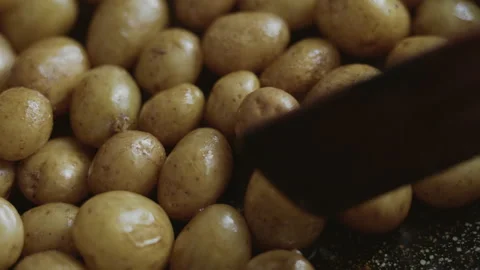 Close-up, stirring whole potatoes fried in oil in a pan with a wooden spatula Stock Footage 337119728
