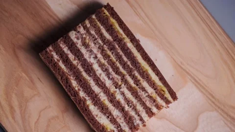 Close-up stop motion video of a striped cake spinning on a wooden board being cu Stock Footage 144072986