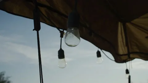 Close up of strand of light bulbs hanging under outdoor patio umbrella Vidéo 234033291
