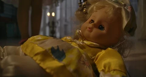 Close-up of strange doll lying on floor in candlelight. Little Caucasian girl's 動画素材 120276218