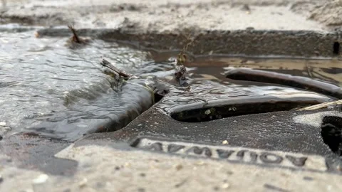 Close-up of a stream of water flowing into a sewer drain Stock Footage 259671563