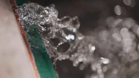 Close-up of a stream of water pouring over. Drops sparkle in the sun Stock Footage 129362817