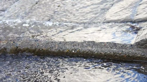 Close-up of streams of water flowing along the city sidewalk Stock Footage 158906963