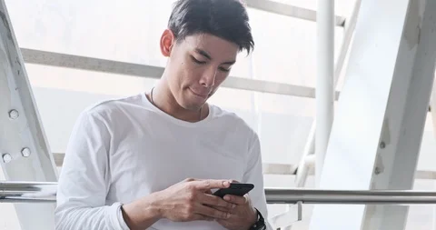 Close up of street kid using mobile phone in overpass. Asian man in white shirt. Stock Footage 106382465