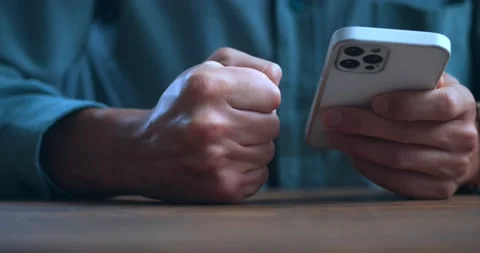 Close-up stressed man uses smartphone and loses his temper reading bad news on Stock Footage 230121018