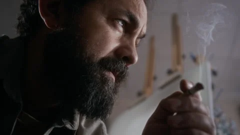 Close Up of Stressed Painter Smoking Cigarette beside Black Canvas in Studio Stock Footage 334684824