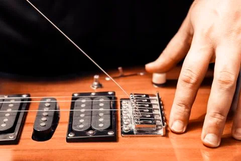 Close-up of string installation through an electric guitar stand. Stock Photos